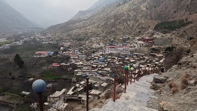 Elevated Marpha village view following stone staircase, prayer flag decorations, valley backdrop Mustang Nepal