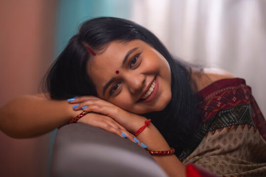 Close-up portrait of a cheerful married woman leaning on sofa and looking at camera at home