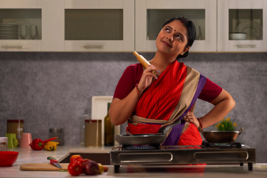 Woman with rolling pin in hand looking up while cooking