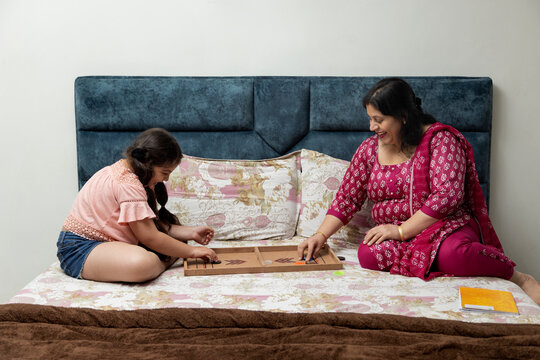 Mother and daughter playing fast sling puck on bed