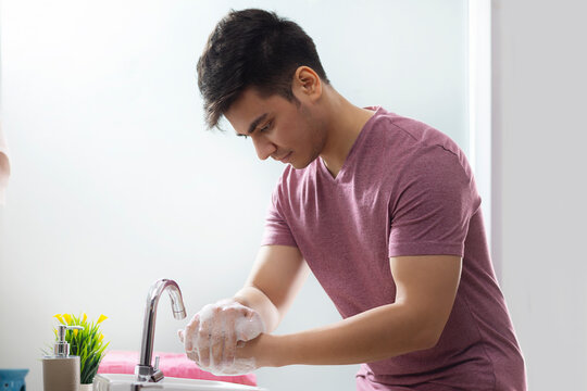 Portrait of young man washing his hands in bathroom