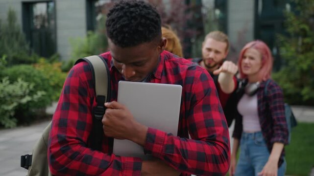 Sad sorrowful lonely African American student guy has problem studying bullying learning in college multiethnic students bully humiliate racial discrimination racism trouble at college high school