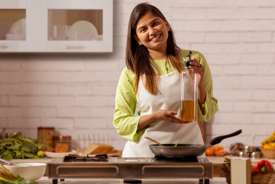 Portrait of cheerful woman cooking in kitchen