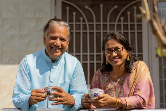 Mature couple having tea while standing in balcony