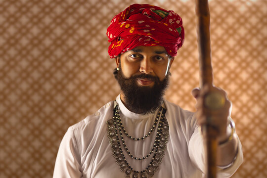 Close-up portrait of Rajasthani young man standing with a stick