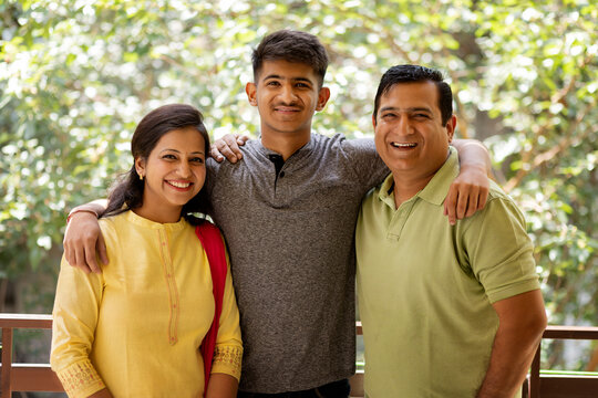  Happy parents with their teenage son standing together on balcony