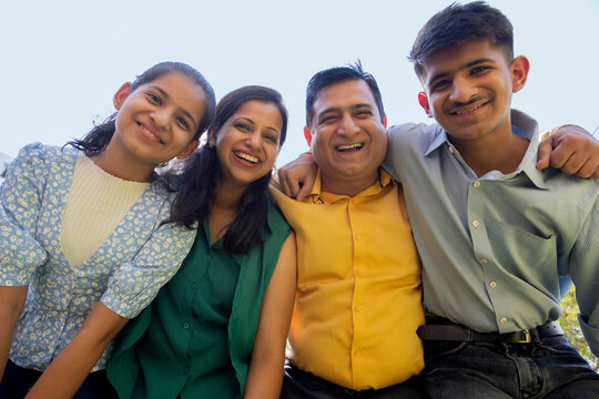 Low angle view of happy Indian family standing together in backyard