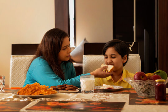 Mother feeding her son during breakfast