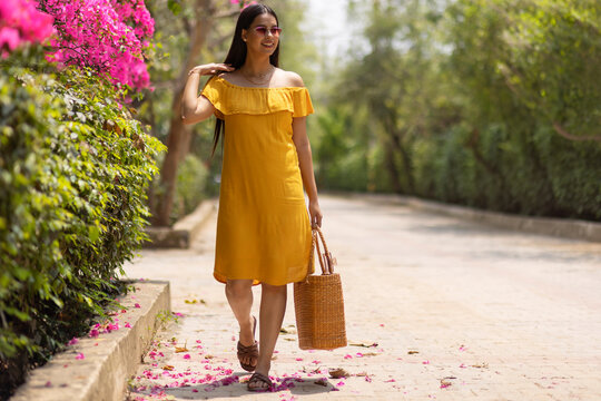 Smiling woman with hand bag walking in the park
