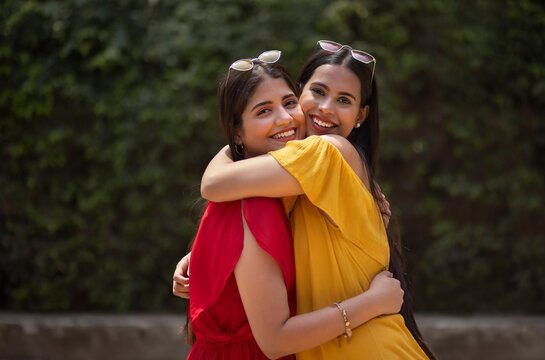 Portrait of two smiling young women embracing in the park