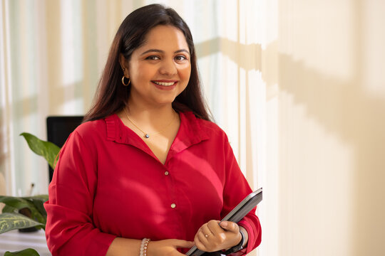 Portrait of a cheerful businesswoman holding a laptop looking at camera
