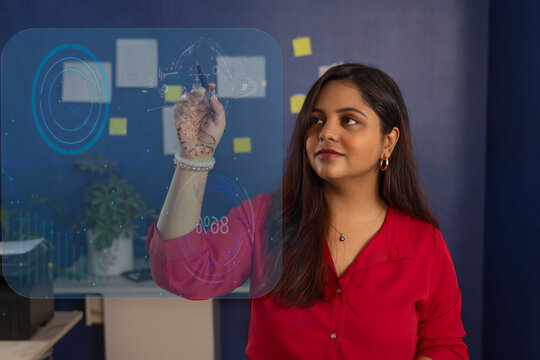 Businesswoman drawing business plan on glass at office�
