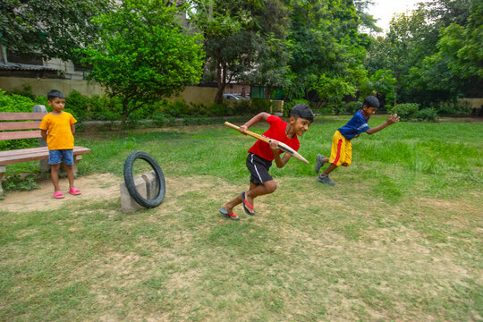 Boy taking a run during a cricket match in the park