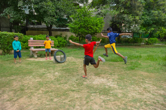 Boy taking a run during a cricket match in the park