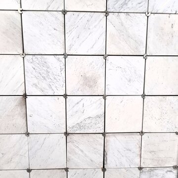 A close-up view of white marble tiles arranged in a precise grid with visible spacers. 
The natural veining and clean layout make this image ideal for construction, interior design, and architectural 