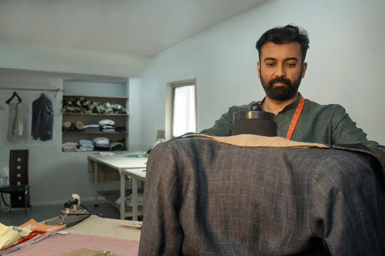 menswear designer working on a bespoke jacket in his studio 