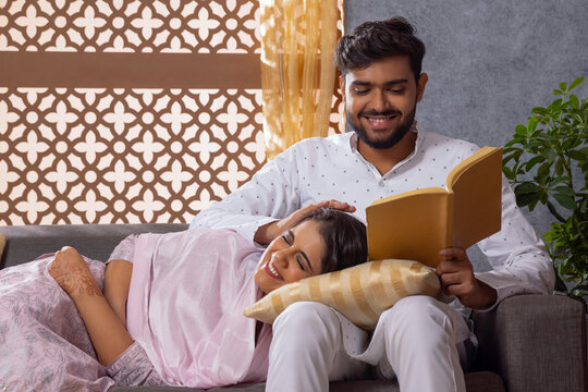 Muslim woman lying on her husband lap on sofa and husband caressing her head