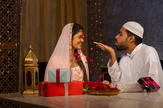 Muslim man blowing rose petals over his wife at home
