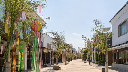 Fototapeta premium Tanabata festival showcasing sunny Japanese pedestrian street lined with bamboo and colorful Tanzaku Paper Cards decorations