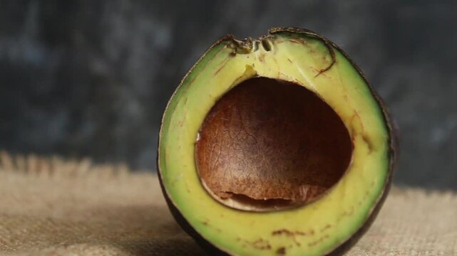 flat lay of a halved avocado on a wooden table against a black background
