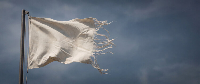 Tattered white flag surrenders against a stormy sky, symbolizing defeat, peace, or the end of conflict, with frayed edges and dramatic clouds for commercial technology, business, marketing