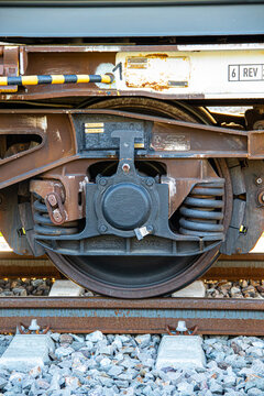 Close-up of a train wheel mechanism and steel suspension on rails. Heavy railway industry and cargo transport concept.