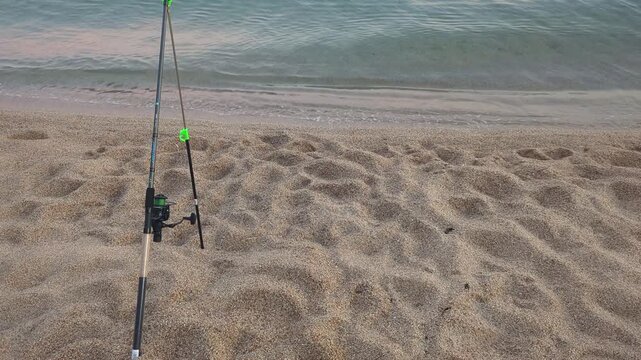 Beach fishing at sunset. A tranquil scene unfolds on the sandy shore. The fishing rod stands ready. Waves gently lap at the coast. Nature invites relaxation and adventure.