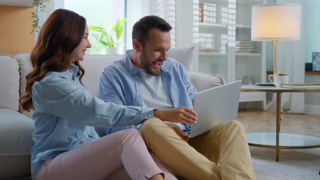 Excited Caucasian using laptop winning in cyberspace screaming with happiness happy family man with woman hugging kissing exciting with computer win discounts lottery prize money reward at home