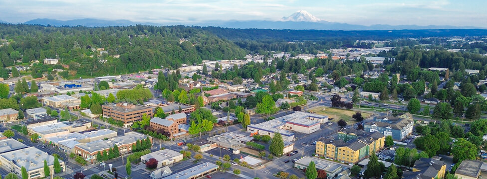 Majestic Rannier mountains overlook expanding commercial districts near Central Kent, Puge Sound great area. Elevated views highlight structural density within evolving urban centers found in WA