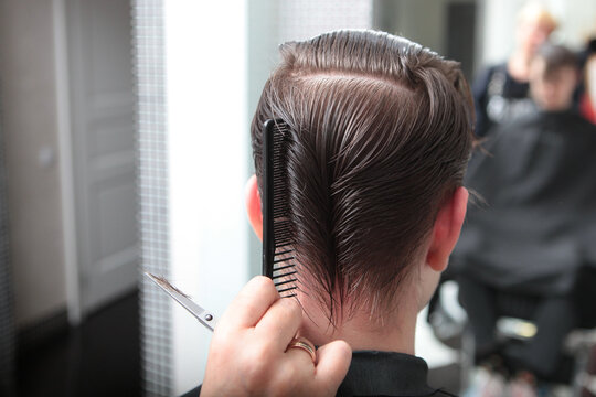 Barbershop. Close-up of man's haircut. Master of barbershop makes haircut with scissors. Giving the haircut perfect shape. Back view