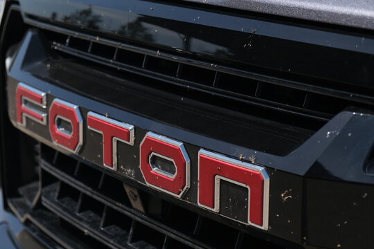 Magnitogorsk, Russia, June 10, 2026. Close up view of black truck front grille featuring red Foton emblem covered with dead bugs after highway driving.