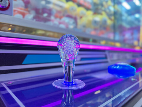 Claw Machine Joystick Close Up with Neon Glowing LED Lights in Arcade Game Room