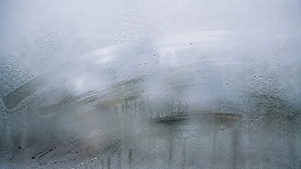 Naklejka premium Condensation on glass window surface with blurred view outside. Water droplet and vapor moisture texture, cold weather concept. Gray background for text overlay or design backdrop effect
