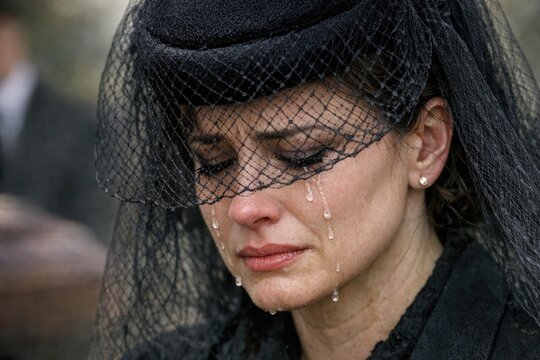 A woman wearing a veil is seen crying, possibly due to emotional distress or loss