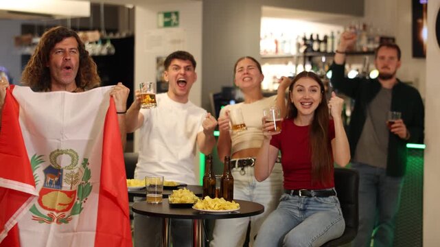 Group of friends fans watching match cheering with Peruvian flag in bar