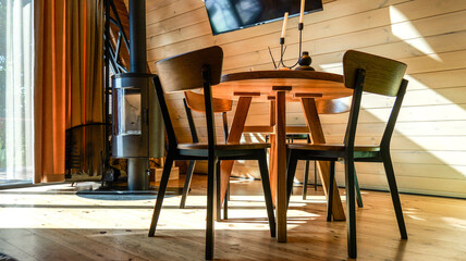 Obraz premium Cozy dining area with modern wood table and chairs next to a sleek wood-burning stove