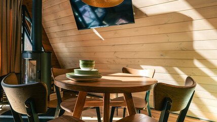 Obraz premium Cozy cabin dining area with wood paneling, modern stove, and table setting