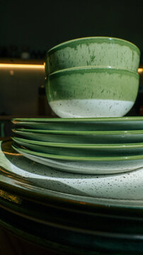 Stack of green speckled ceramic bowls and plates on a countertop