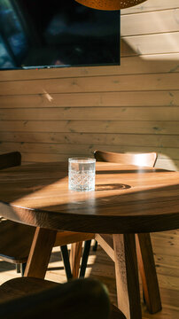 Glass of water on a wooden table bathed in warm sunlight