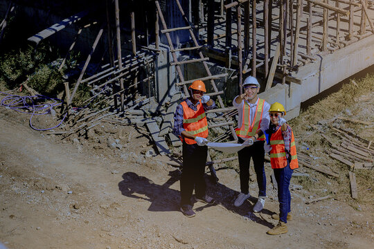 Structural engineer, architect and foreman worker with blueprints discuss, plan working for the outdoors building construction site. Construction collaboration concept