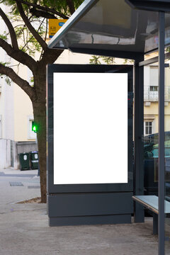 Blank advertising billboard integrated into a modern bus stop shelter in an urban environment. The empty poster display provides copy space for marketing campaigns, outdoor advertising