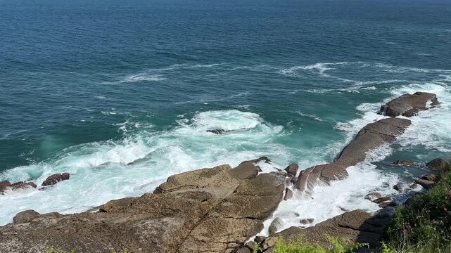 Atlantic surf cascades over massive rock formations, creating a natural waterfall of turquoise water and white sea foam. Seagulls glide above the shoreline on coastal air currents, highlighting the wi