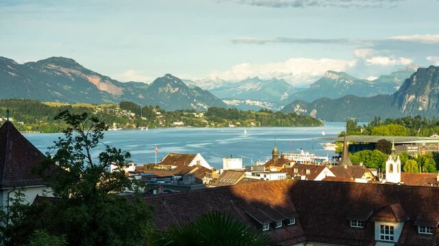 Time lapse of Lucerne cityscape and Lake Lucerne with moving clouds over the Swiss Alps, scenic view of European old town rooftops and passing boats