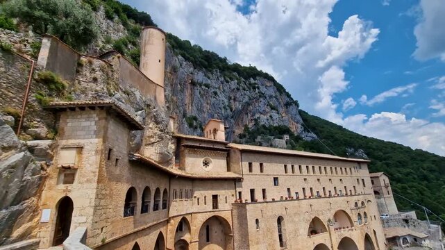 Sacro Speco Subiaco Italy 4K. Handheld panning view of medieval San Benedetto monastery built into steep rock cliff. Famous sacred pilgrimage destination in green mountains b roll video no people