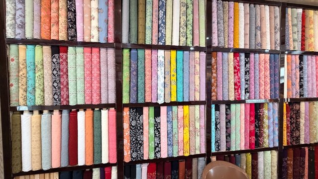 Colorful Pakistani fabric store shelves with patterned and embroidered unstitched dress materials.