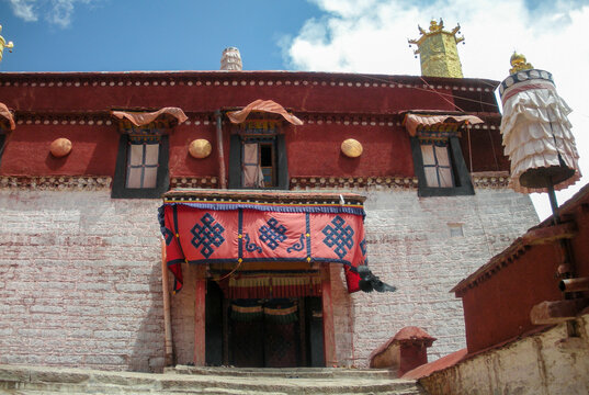 Colorful facade of a traditional monastery in Tibet, China. Entrance door in the foreground. Blue sky on the background.
