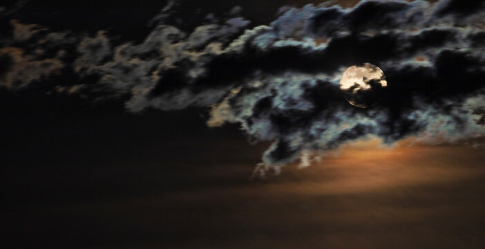 Full moon peeking through the clouds in Southern Arizona