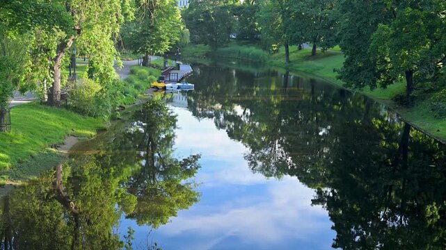 Riga Canal reflecting the summer sky and park trees in Latvia