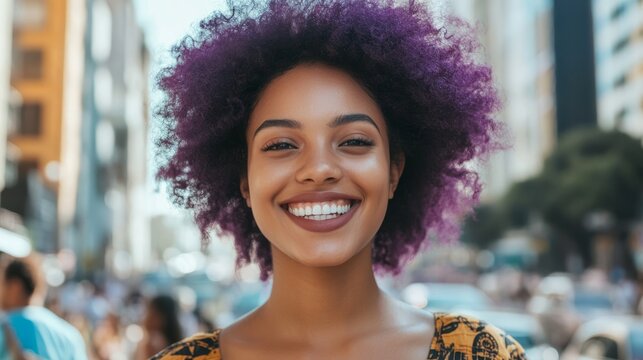 Smiling woman with curly purple hair stands confidently in a vibrant urban setting, showcasing joy and positivity amidst a bustling street scene filled with life