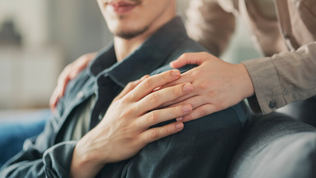 The young woman comforting her husband by touching his shoulder